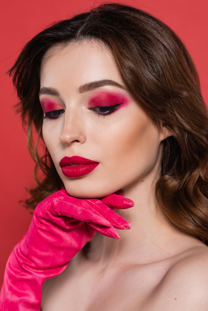 portrait of pretty young woman with magenta color eye shadow posing isolated on pink  - Valokuva, kuva