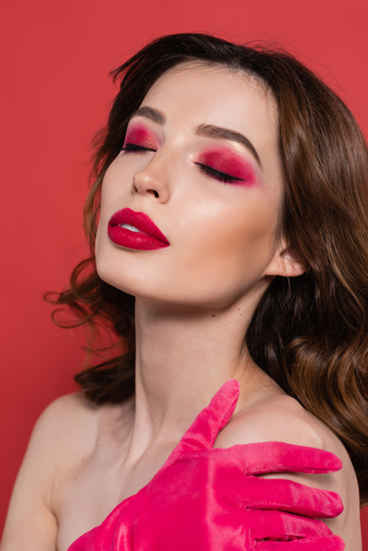 portrait of young woman with magenta color eye shadow and closed eyes isolated on pink  - Foto, Bild