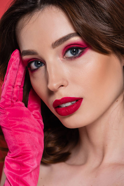 close up of young woman with magenta color eye shadow isolated on pink  - Zdjęcie, obraz