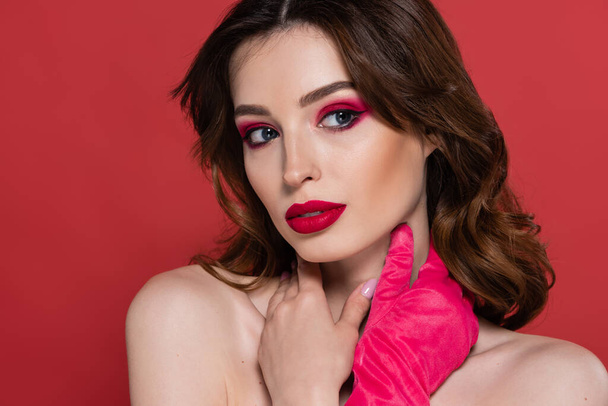 portrait of young woman with magenta color eye shadow and bright glove posing isolated on pink  - Foto, afbeelding