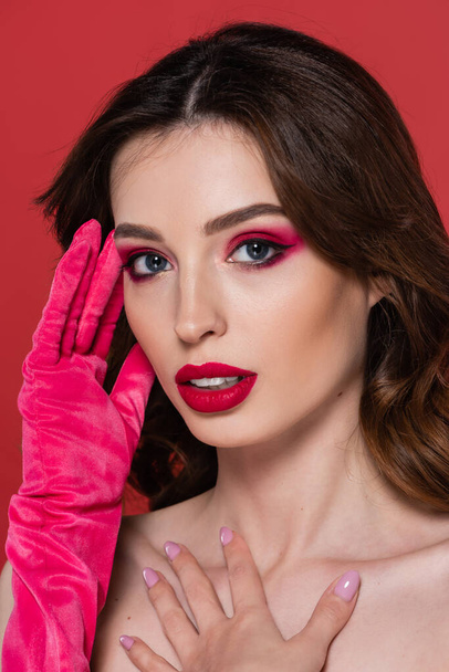 young woman with magenta color eye shadow and bright glove posing isolated on pink - Photo, image
