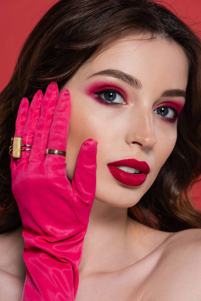 portrait of young woman with magenta color makeup and glove with golden rings isolated on pink  - Foto, Bild