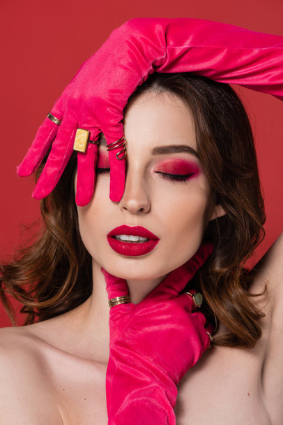 portrait of young woman with magenta color makeup posing in gloves with golden rings isolated on pink  - Φωτογραφία, εικόνα