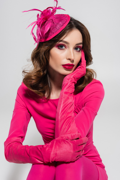 portrait of young brunette woman in elegant hat and magenta color gloves isolated on grey  - Fotó, kép