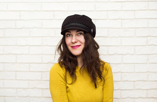 Portrait of a brunette in a hat on a light background - Photo, Image