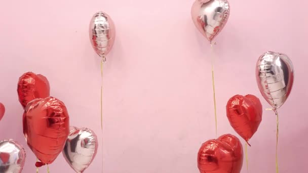 Bella coppia a San Valentino festeggiare il 14 febbraio, amore. Donna e uomo che si baciano dietro palloncini cuori rossi, appuntamento romantico, abbraccio, carino - Filmati, video