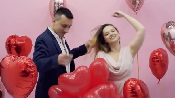 Ystävänpäivä juhlii 14. helmikuuta. Nainen ja mies suudella takana ilmapalloja punainen sydämet, romanttinen päivämäärä, halata, söpö - Materiaali, video
