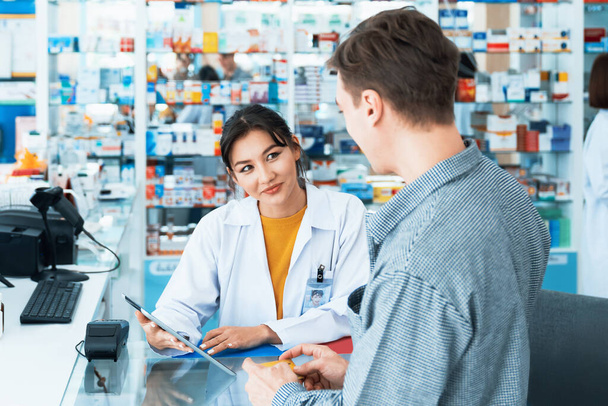 Payment by credit card with payment terminal in qualified drugstore. Modern financial payment of electric money. Caucasian customer purchase medication in pharmacy with prescription from pharmacist. - Foto, Bild