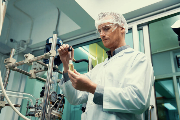 Egy tudós vagy patikus CBD kenderolajat von ki gyógyászati célokra egy laboratóriumban. A kannabiszkivonó gépből előállított alternatív kannabiszalapú gyógyszer. - Fotó, kép