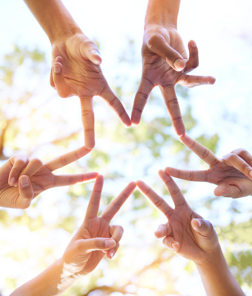 Руки разом, знак зірки та командний жест сонця з рукою, щоб показати групову роботу та спільноту. На відкритому повітрі, лінза спалахує і нижче людей, які працюють в команді з друзями, демонструючи прихильність і солідарність
. - Фото, зображення