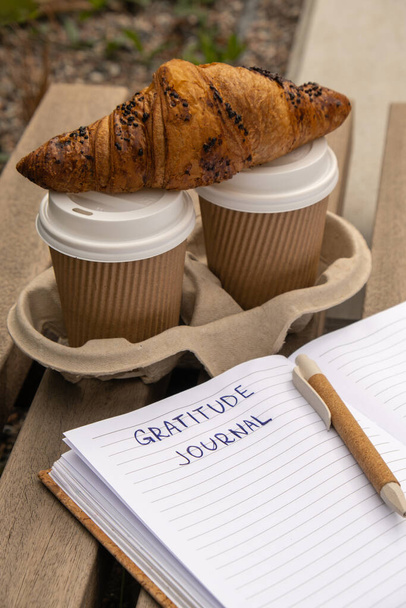 Writing Gratitude Journal on wooden bench. Coffee and croissants morning routine. Today I am grateful for. Self discovery journal, self reflection creative writing, self growth personal development concept. Self care wellbeing spiritual health, being - Photo, Image