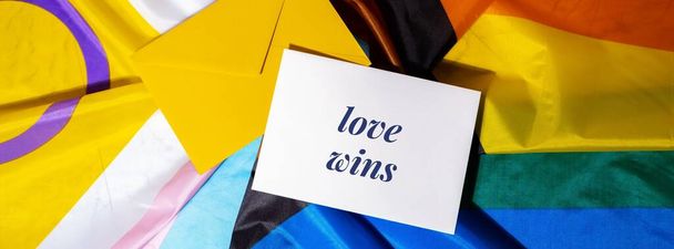 LOVE WINS text on valentine card inscription positive quote phrase Greeting card on Rainbow LGBTQIA flag made from silk material. Symbol of LGBTQ pride month. Equal rights. Peace and freedom. Support LGBTQIA community. Diversity equality - Foto, afbeelding