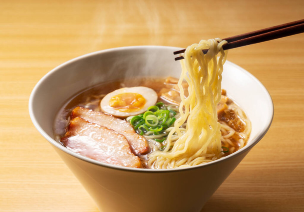 Hot ramen noodles with steamy water on the table. Scoop it up with chopsticks. - Foto, imagen