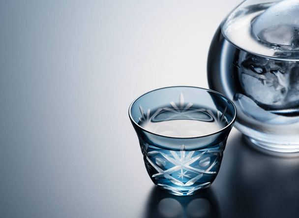 Sake poured into a faceted glass against a black background. The image of sake.  - Fotó, kép