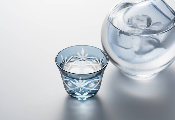 Sake poured into a faceted glass on a white background. The image of sake. - Fotó, kép