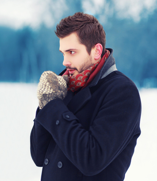 Handsome man in mittens freezes outdoors in winter cold day - Fotó, kép