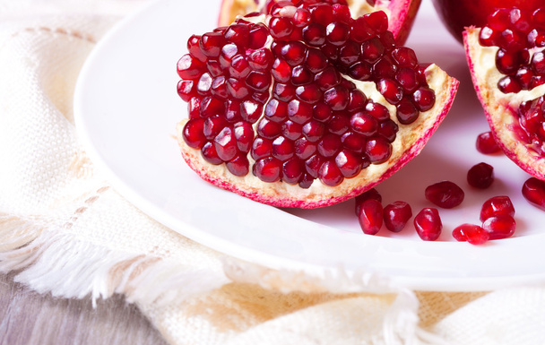 Closeup sliced pomegranate on white plate - Photo, Image