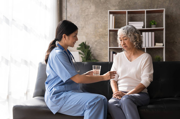 Healthcare worker or nurse caregiver giving pills, showing a prescription drug to senior woman. Elderly healthcare concept.. - Photo, Image