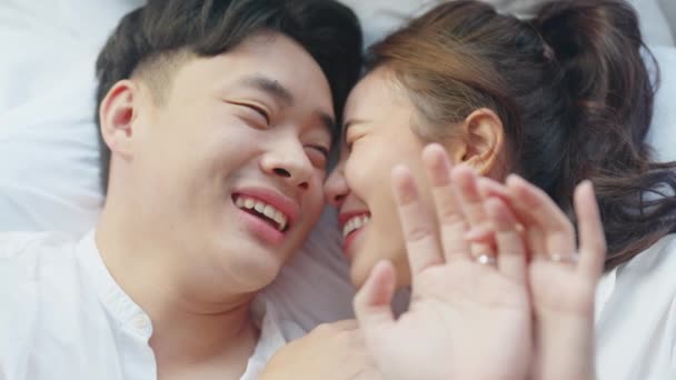 Top view young couple asia people lying down talk on bed relax smile hold hands look at ring on finger. Sweet happy lover asian man woman fall in true love new family life begin just married moment. - Footage, Video