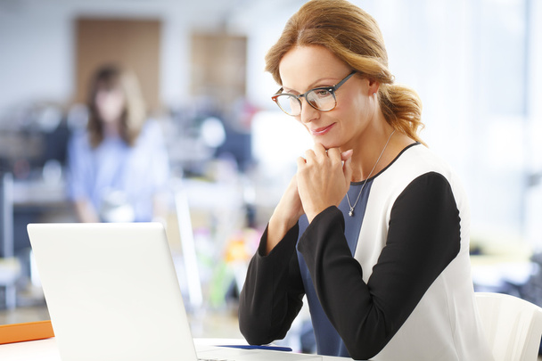 Businesswoman sitting in front of laptop - Фото, изображение