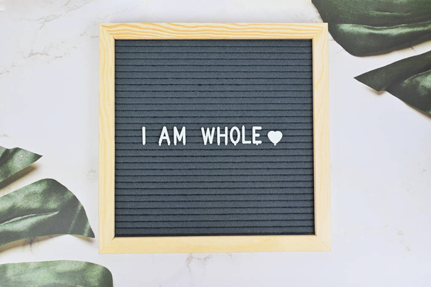 Grey letter board with phrase I am whole, self love, self care on natural background. Mindfulness lifestyle, mental health. Aspiration and supportive sentence - Foto, imagen