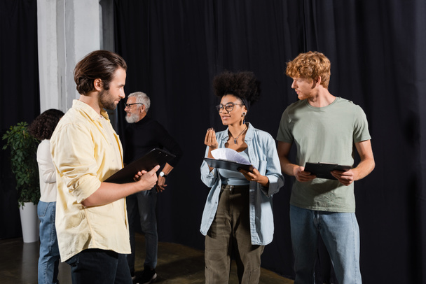 smiling african american woman with scenario talking to young actors in acting skills school - Photo, image