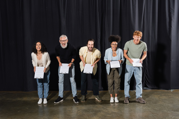 excited actors with bearded screenwriter looking at camera and laughing on stage in theater - 写真・画像