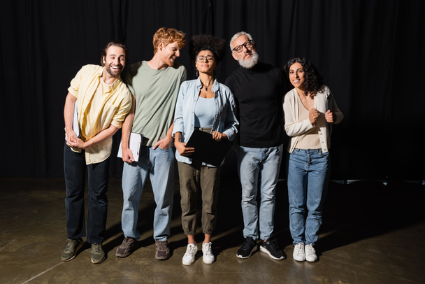 young emotional actors standing on theater stage near grey haired screenwriter - Photo, Image