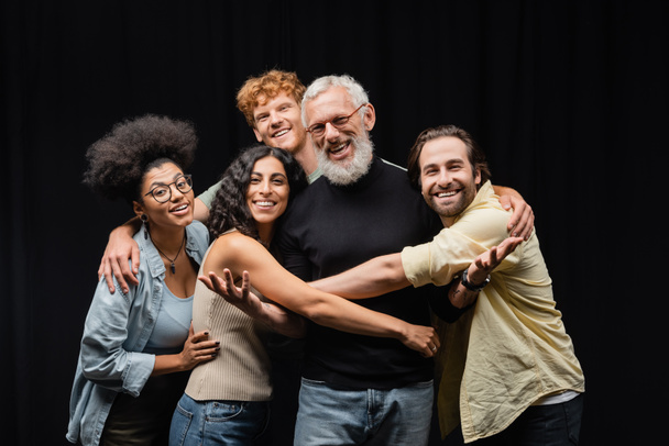 cheerful multiethnic actors embracing grey haired art director in theater  - Foto, Imagen