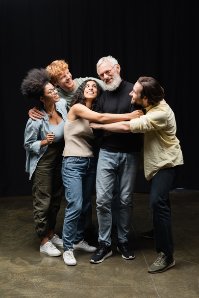 happy multicultural students hugging acting skills teacher in theater school - Foto, Imagen