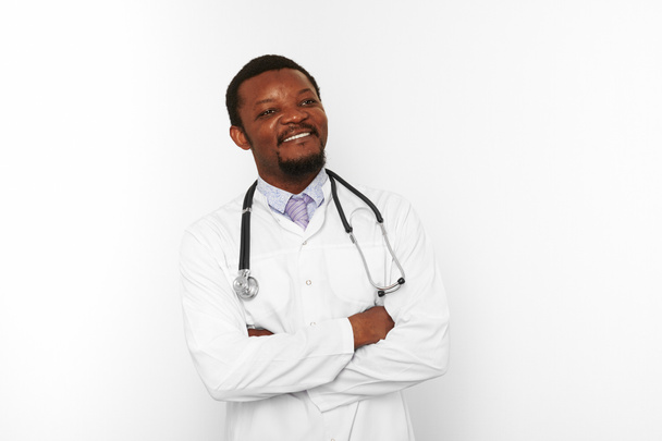 Усміхнений чорний бородатий лікар схрестив руки в білому пальто зі стетоскопом ізольовано на білому тлі. Дорослий чорношкірий афроамериканський лікар-терапевт портрет, впевнені відверті чоловічі емоції
 - Фото, зображення
