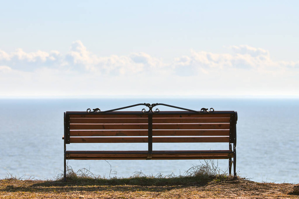 Empty bench on cliff before sea background, peaceful and quiet place for thinking alone, loneliness and loss of loved one concept. Pacifying view of marine horizon of Azov sea in Russia - Foto, afbeelding