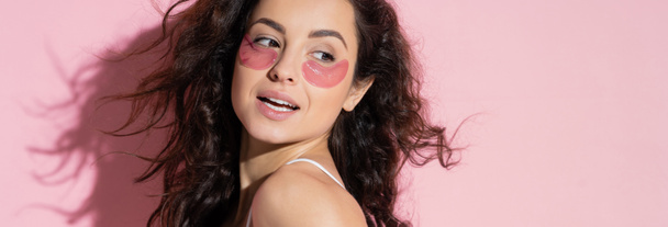 Positive young woman with hydrogel eye patches standing on pink background, banner  - Photo, image