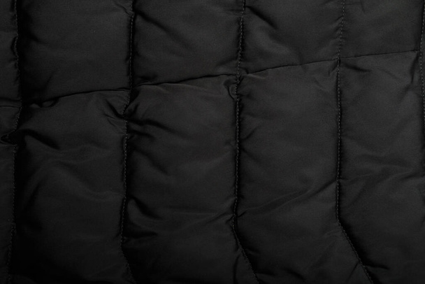stitched down jacket or quilted outer garments black fabric texture background - Foto, Imagen