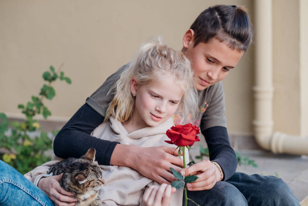 Teen in love on a date. First kids love, teenager boy giving flower to girl.Happy children portrait - Photo, Image