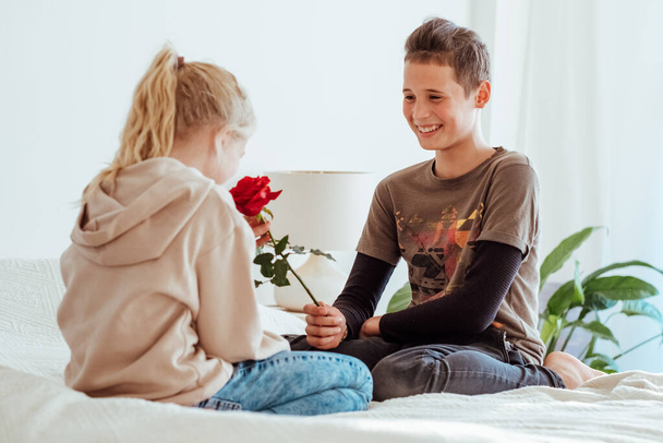 Teen in love on a date. First kids love, teenager boy giving flower to girl. Happy children portrait . - Fotoğraf, Görsel