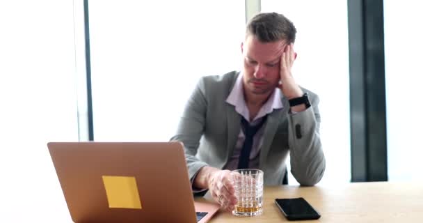 Drunk businessman in suit drinking whiskey from glass in front of laptop 4k movie slow motion. Alcohol addiction concept - Záběry, video