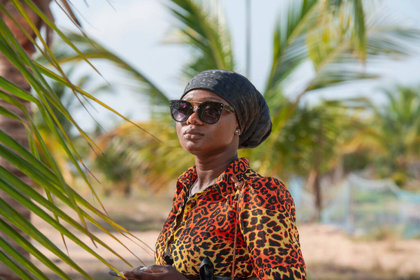 Жінка з чорним головним убором і сонячними окулярами захищає від сонця на пляжі в Кета Гана Західній Африці.. - Фото, зображення