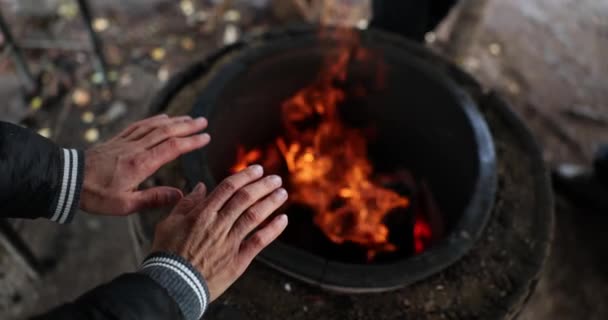Homeless man warming his hands by fire on street closeup 4k movie slow motion. Life of people without fixed place of residence concept  - Footage, Video