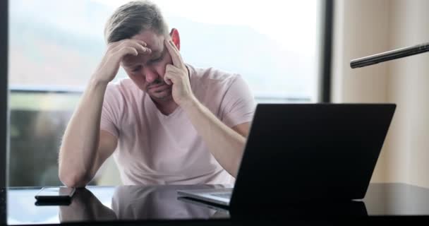 Frustrated tired businessman sitting at table near laptop 4k movie slow motion. Emotional burnout in business concept  - Záběry, video