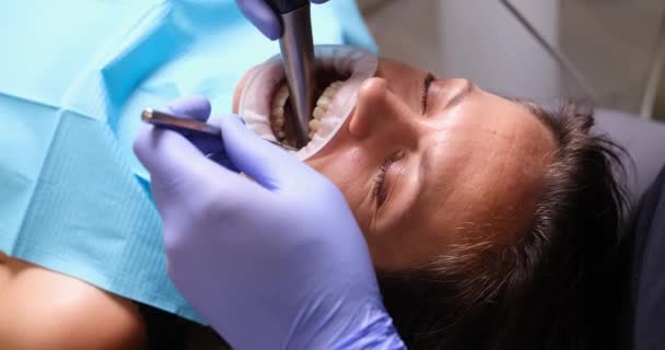 Doctor dentist treating teeth to female patient using tools and drill in clinic 4k movie slow motion. Dental care for acute toothache concept  - Footage, Video
