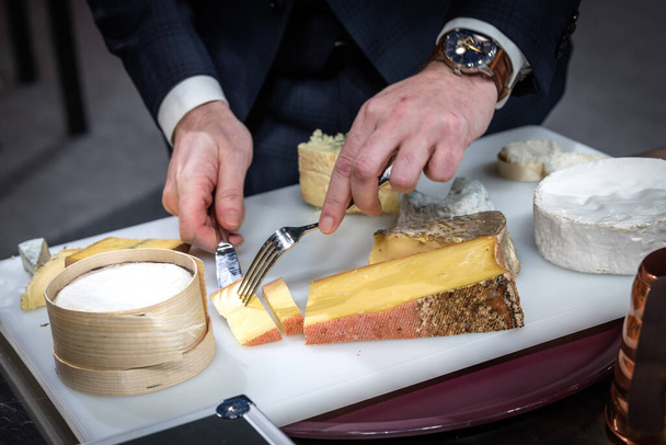 a waiter is cuting a cheese for his client in a hotel - Foto, Imagem
