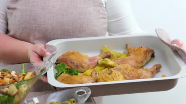 close-up of beige baking sheet on white background with chicken ham baked apple potato baked salad woman with large breasts holds and turns baking sheet holds with potholders food appetite ad - Πλάνα, βίντεο