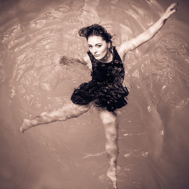 Mulher flutuando na piscina em vestido preto
. - Foto, Imagem