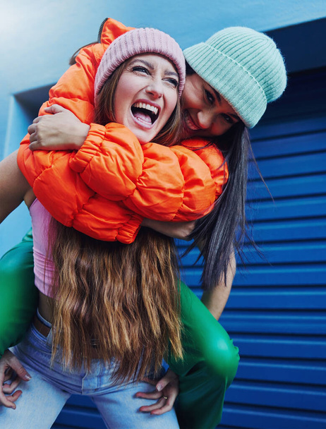 Friends, city fashion and piggyback girl with outdoor adventure, funny and comic face with happiness together. Gen z women, metro and blue background for trendy clothes, smile and happy in street. - Valokuva, kuva
