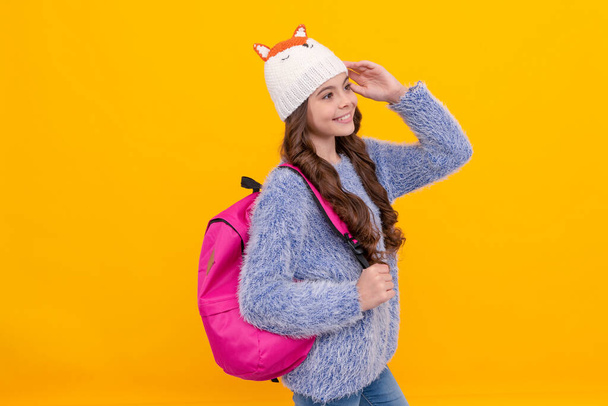 happy teen girl wear hat with schoolbag on yellow background, school. - Photo, image