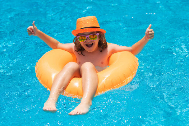 Kid in sunglasses in pool in summer day. Children playing in swimming pool. Summer holidays and vacation concept - Photo, Image