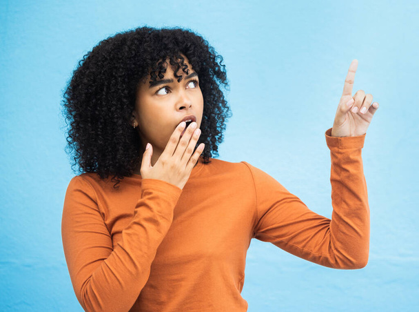 Black woman, surprise face and pointing in studio for news, announcement or gossip notification by blue background. Gen z girl, young african model and fashion with wow hand sign for hearing secret. - Φωτογραφία, εικόνα