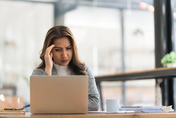 азиатская женщина много думает о решении проблем в Интернете глядя на экран ноутбука, обеспокоенные серьезные азиатские деловая женщина сосредоточена на решении сложной работы компьютерной задачи.. - Фото, изображение
