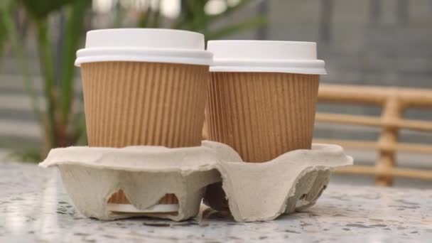Two paper cups with lid for tea to go. Coffee take away on the table. Take-out coffees with brown paper cup holder. Brown safety cardboard collars. Take away box for cups. Cardboard tray - Footage, Video